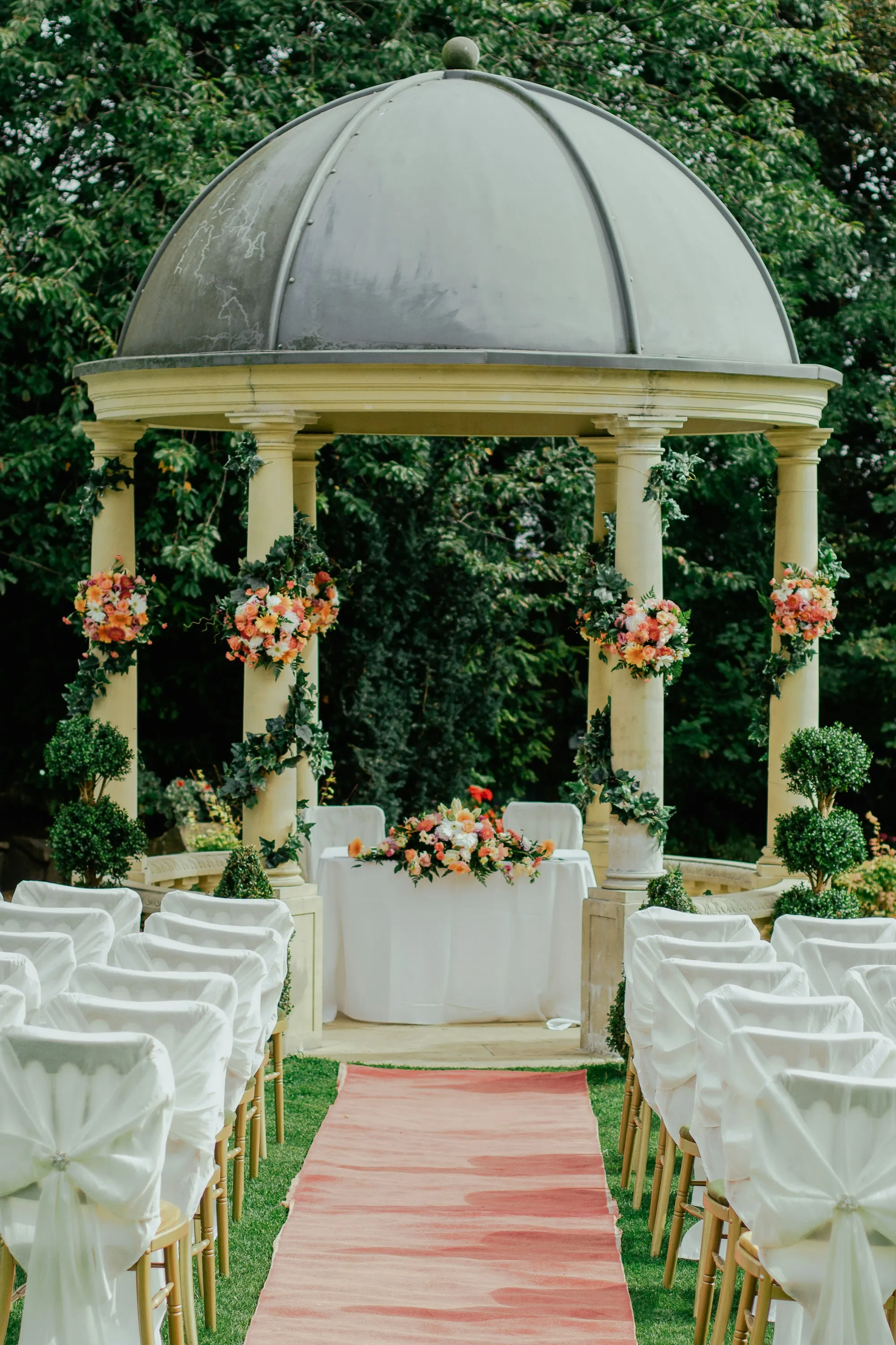 Gazebo blanco decorado con flores y vegetación para una ceremonia