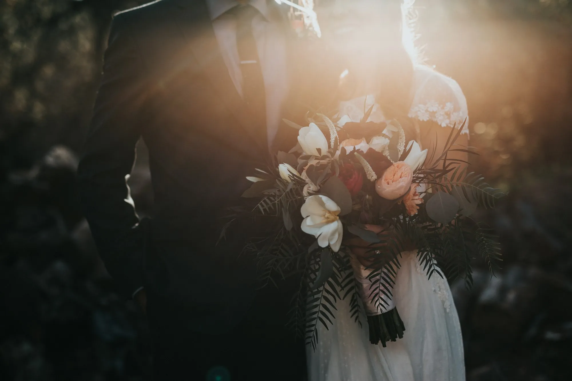 Novia con su ramo entre los árboles de un bosque al atardecer